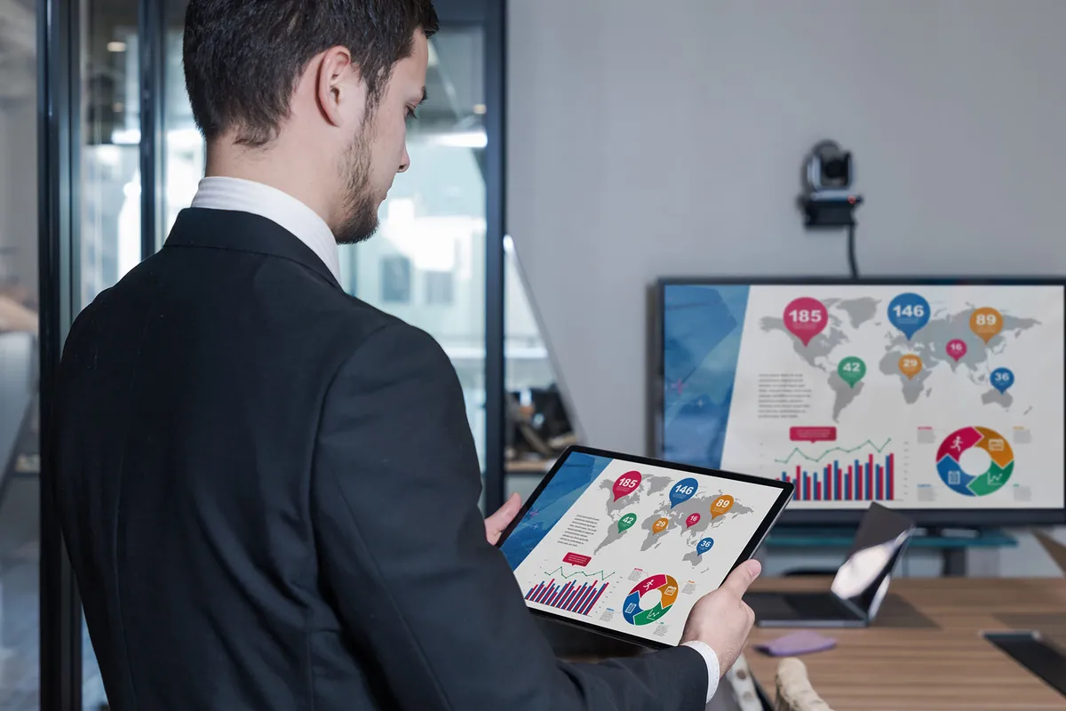 Tabletinden toplantı ekranına kablosuz sunum yapan çalışan
